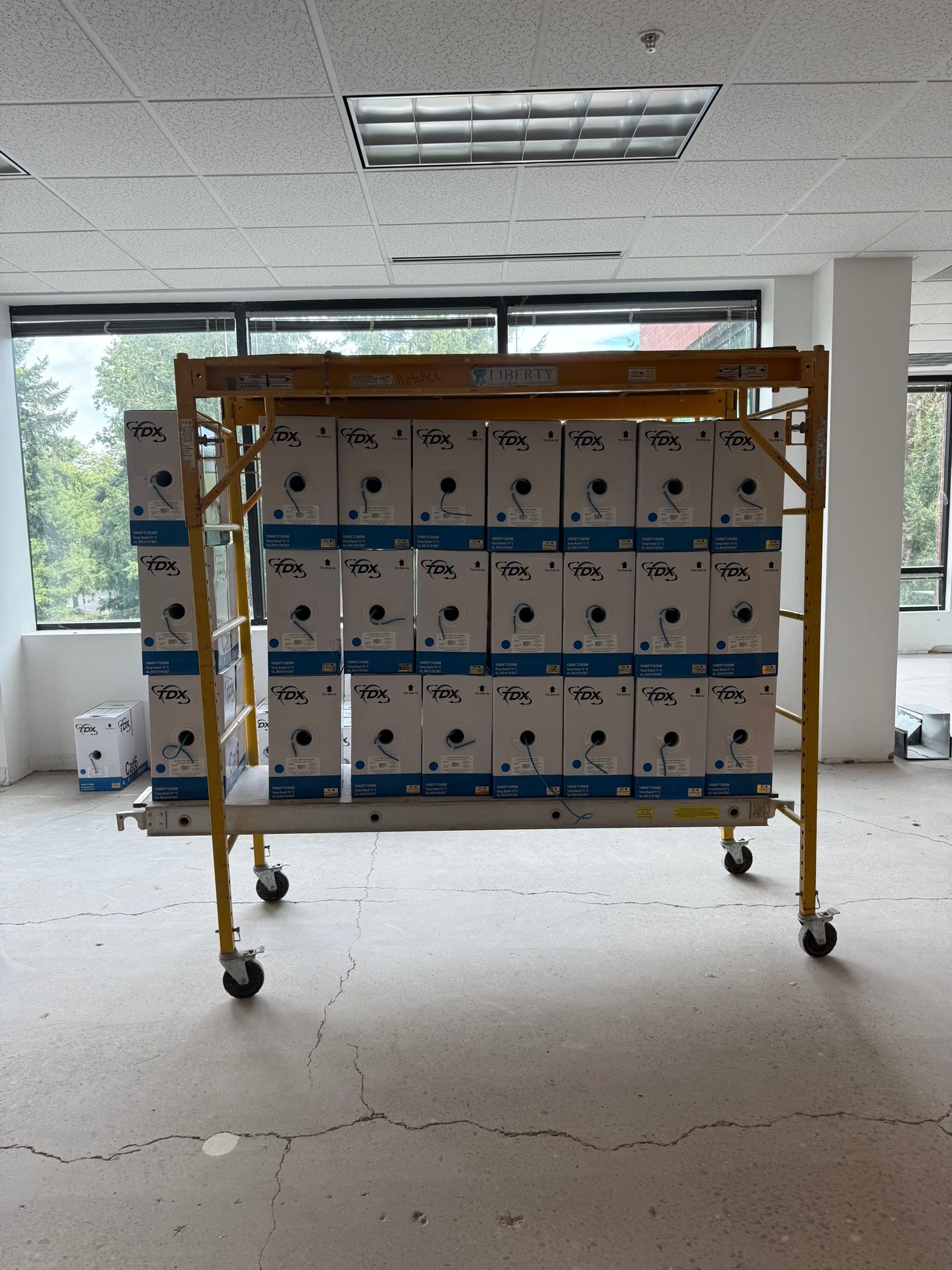 Rolling cart stacked with boxed cable spools staged in an unfinished office.