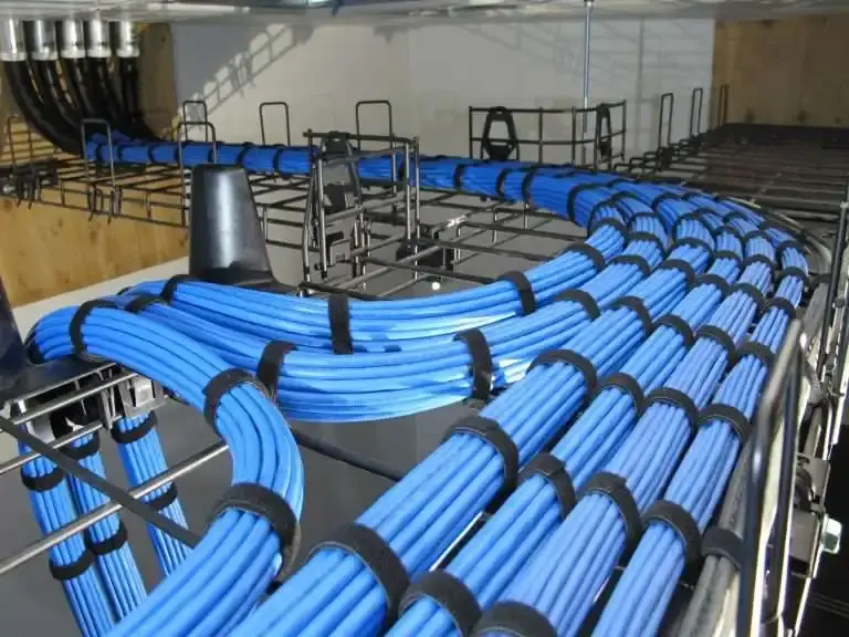 Overhead cable-tray shot of bundled blue cable runs across a ladder rack.