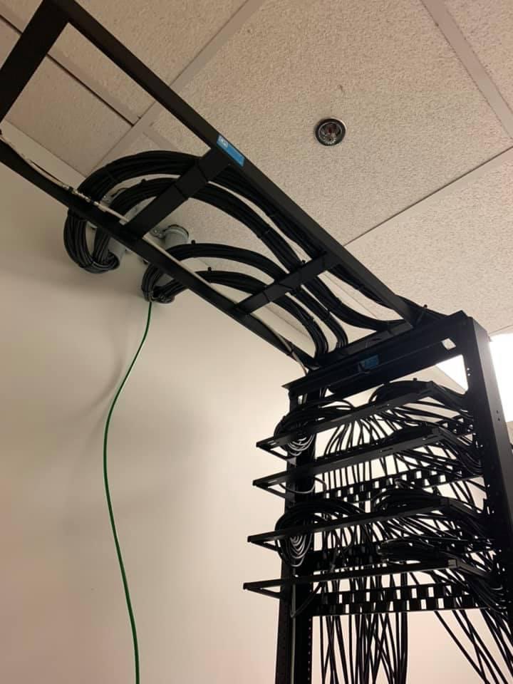 Rack cable-management bay with looped black cable and a green ground wire.