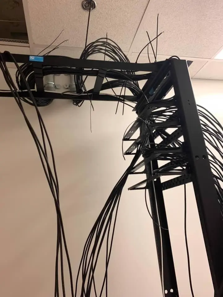 Rack cable-management arm feeding a vertical rack, cable dressed along the tray.