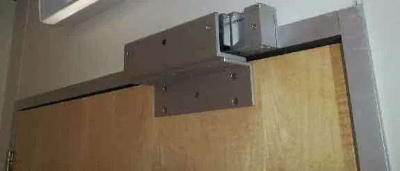 An electromagnetic door lock mounted above a door frame, install in progress