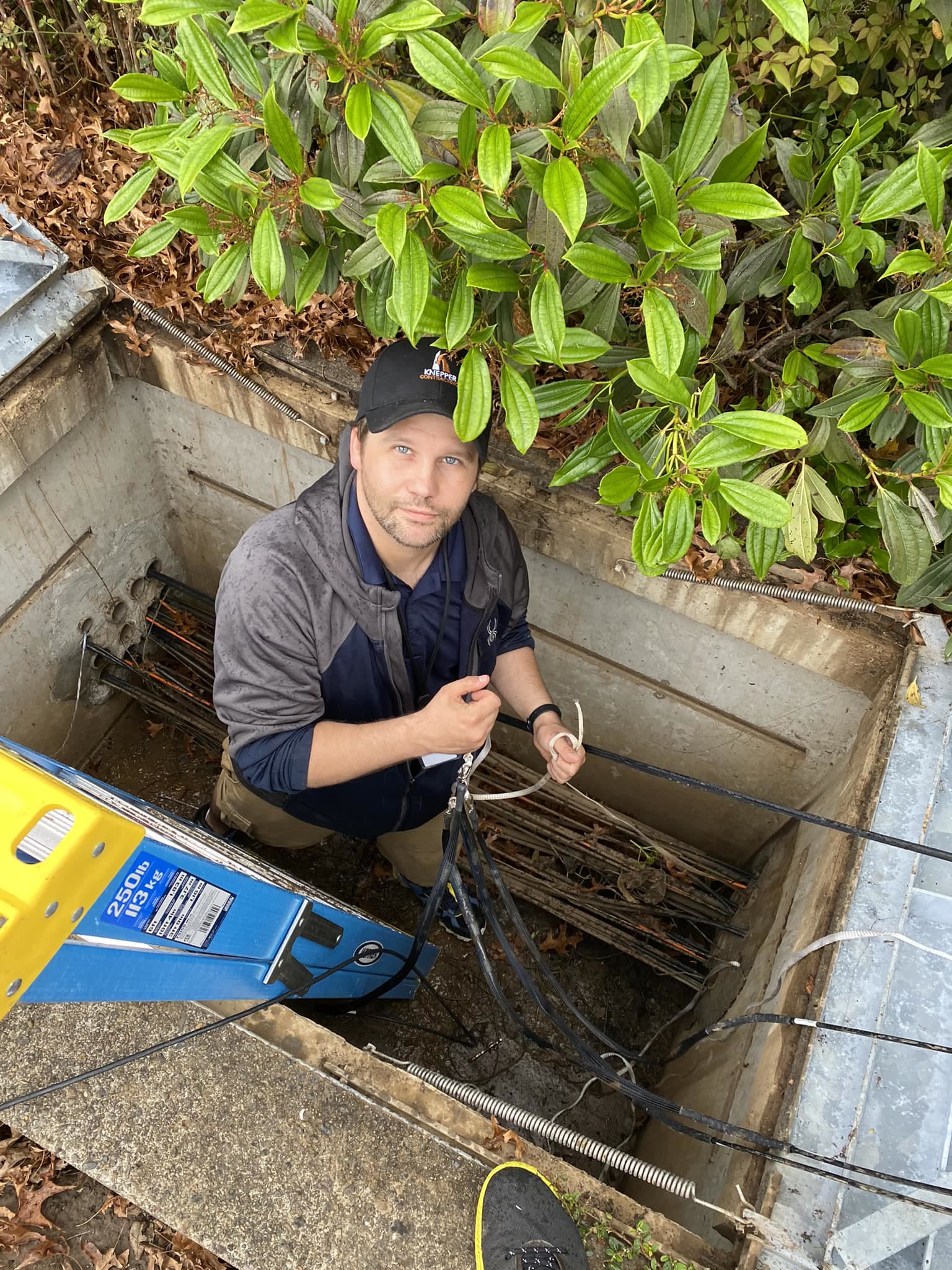 A technician in a Knepper cap dressing cables in an underground utility vault