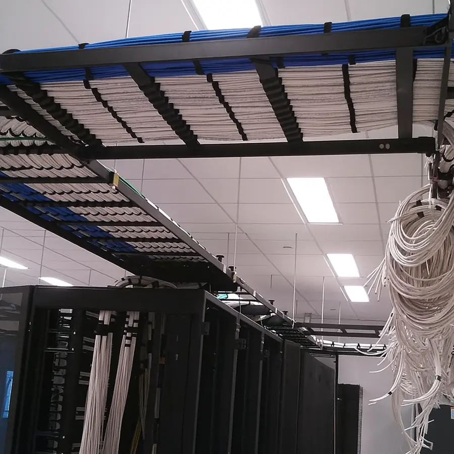 Real MDF/server room: cable ladder racks stacked with dressed bundles feeding server racks.