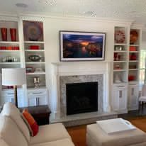 Television mounted above a stone fireplace with built-in shelving on either side.